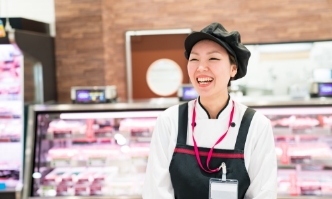 Smiling grocery store employee in front of the meat case
